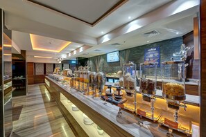 A hotel reception area with a buffet counter displaying various food items. - Omega Hotel (Dubai)