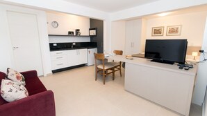 A compact living space with a kitchenette, a dining area, and a seating area with a red sofa. - Morada Clariana (Curitiba)