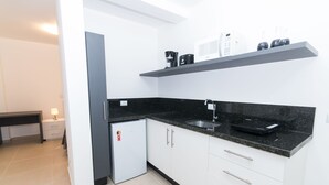 A modern kitchen with white cabinets, a black countertop, a built-in microwave, and a coffee maker. - Morada Clariana (Curitiba)
