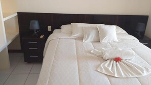 A neatly made bed with white linens and a decorative pillow arrangement.