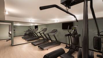 Ein Fitnessstudio mit Laufbändern, einer Gewichtbank und Trainingsgeräten.