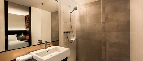 A modern bathroom with a large mirror, a white sink, and a shower with a handheld showerhead.