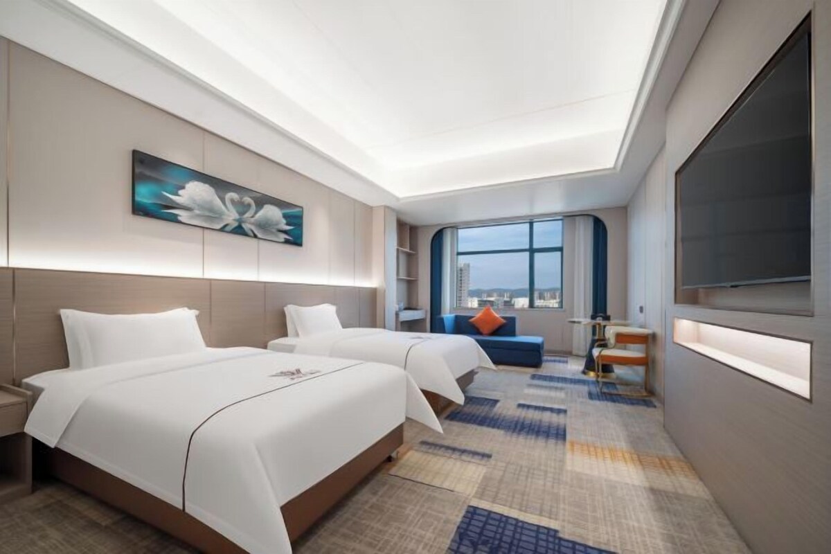 A hotel room with two beds, a large window, a city view, and a modern design.