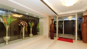 A modern hotel lobby with a glass entrance, decorative vases, and a red carpet. - Willman Hotel (Dongguan)