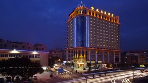 A high-rise hotel with a prominent corner entrance and illuminated signage. - Willman Hotel (Dongguan)