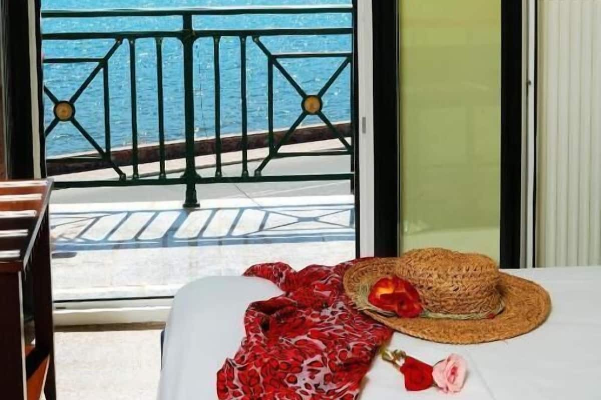 Una habitación con una cama, un sombrero de paja y una manta roja con motivos florales.