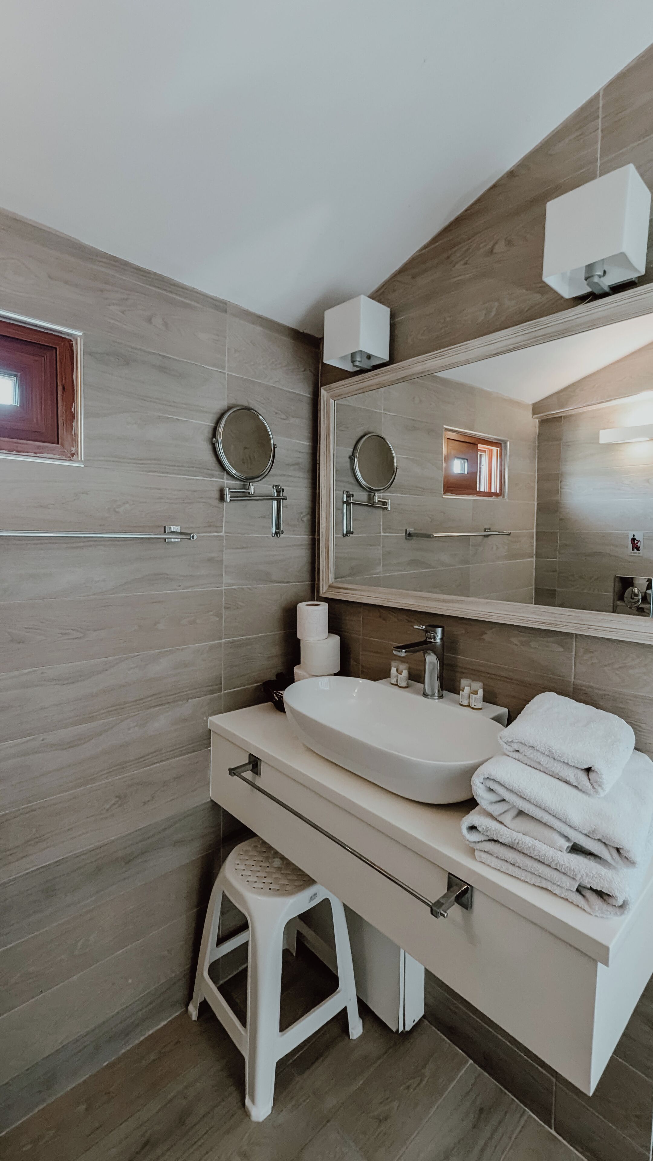 A modern bathroom with a large sink, two mirrors, and a toilet.