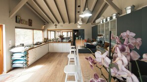 Een ruime keuken met houten vloer, witte barstoelen en hanglampen.