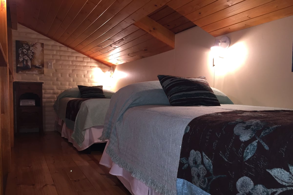 Una camera accogliente con due letti, travi in legno al soffitto e una parete in mattoni.