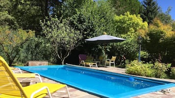 Una piscina al aire libre de temporada, sombrillas