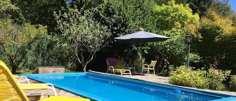 Una piscina al aire libre de temporada, sombrillas