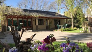 A building with a tiled roof, a garden with flowers, and outdoor seating. - El Colibri Cabañas de la Naturaleza (Trelew)