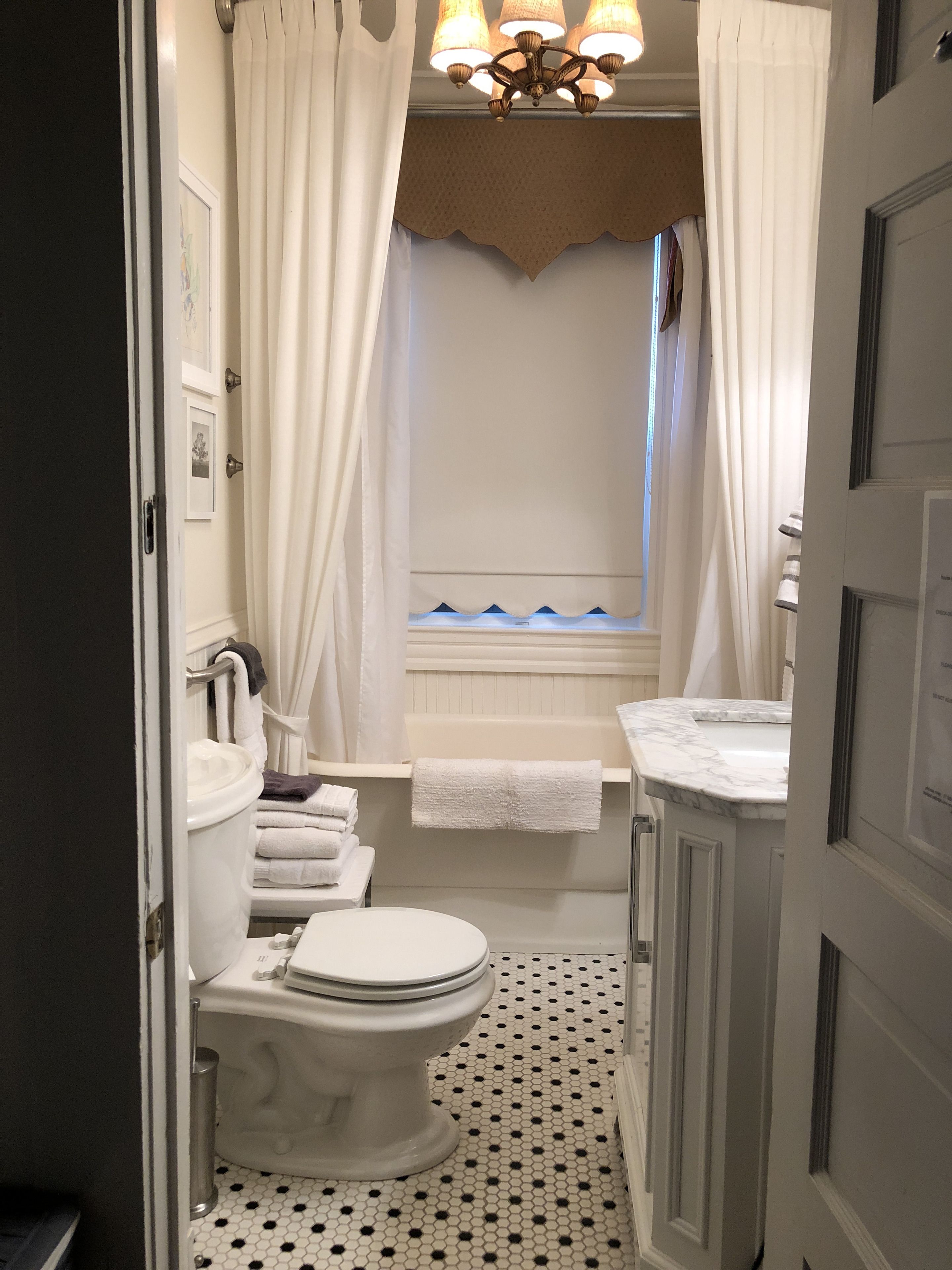 Une salle de bain équipée de toilettes, d’un lavabo et d’une baignoire. On y trouve des serviettes et un rideau de douche.
