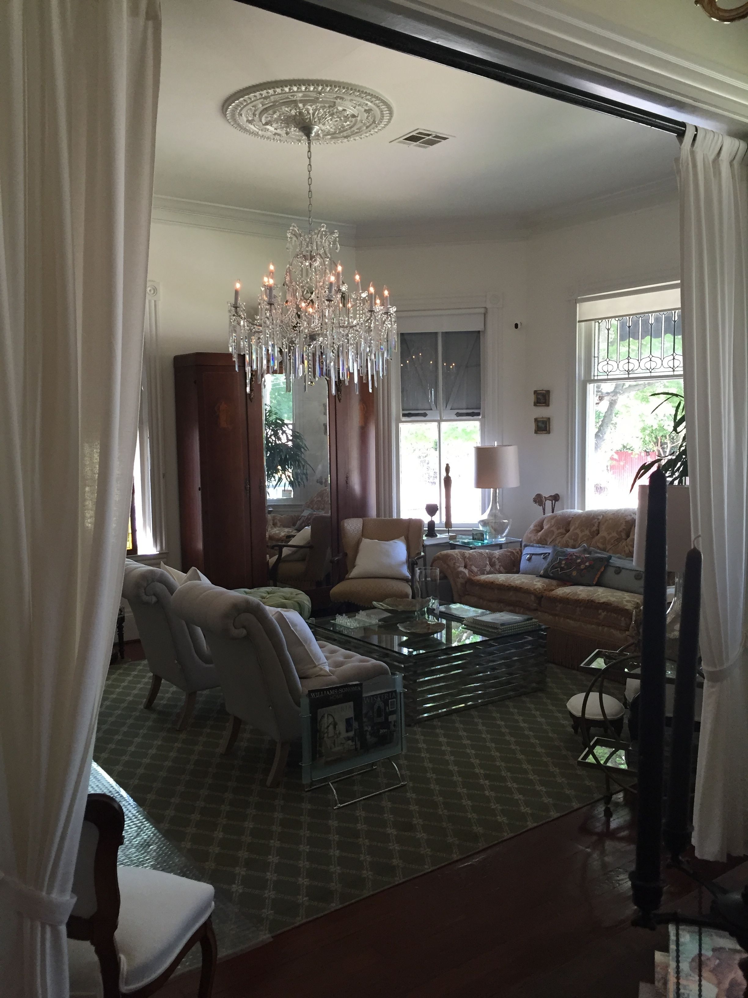 A spacious living room with a chandelier, comfortable seating, and a large window with a view.