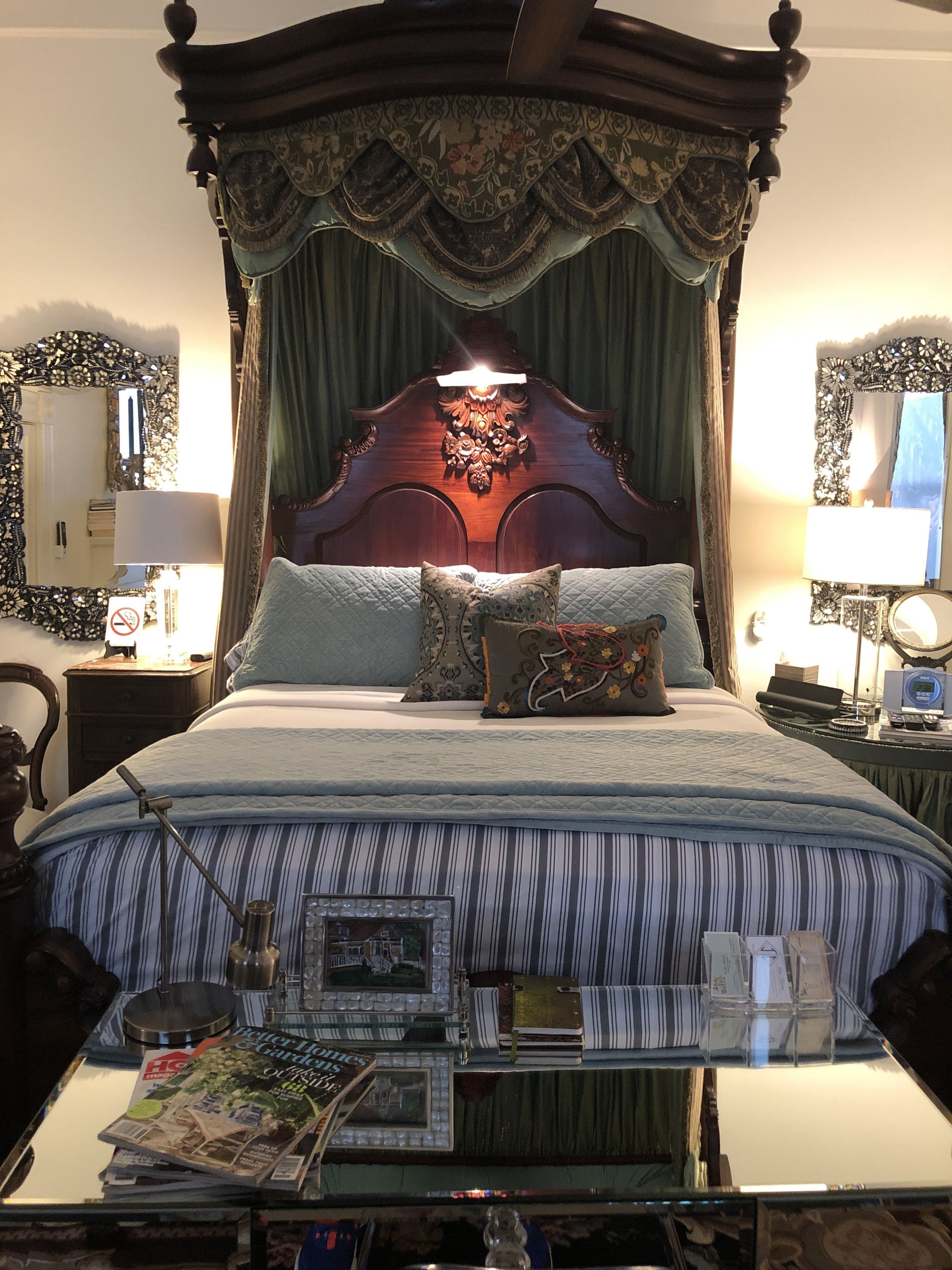 Un lit à baldaquin, une table de chevet avec une lampe et un porte-revues.