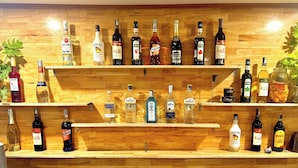 A wooden bar with shelves displaying various bottles of alcohol. - Tuan Ngoc Hotel (Nam Hoa Lu)