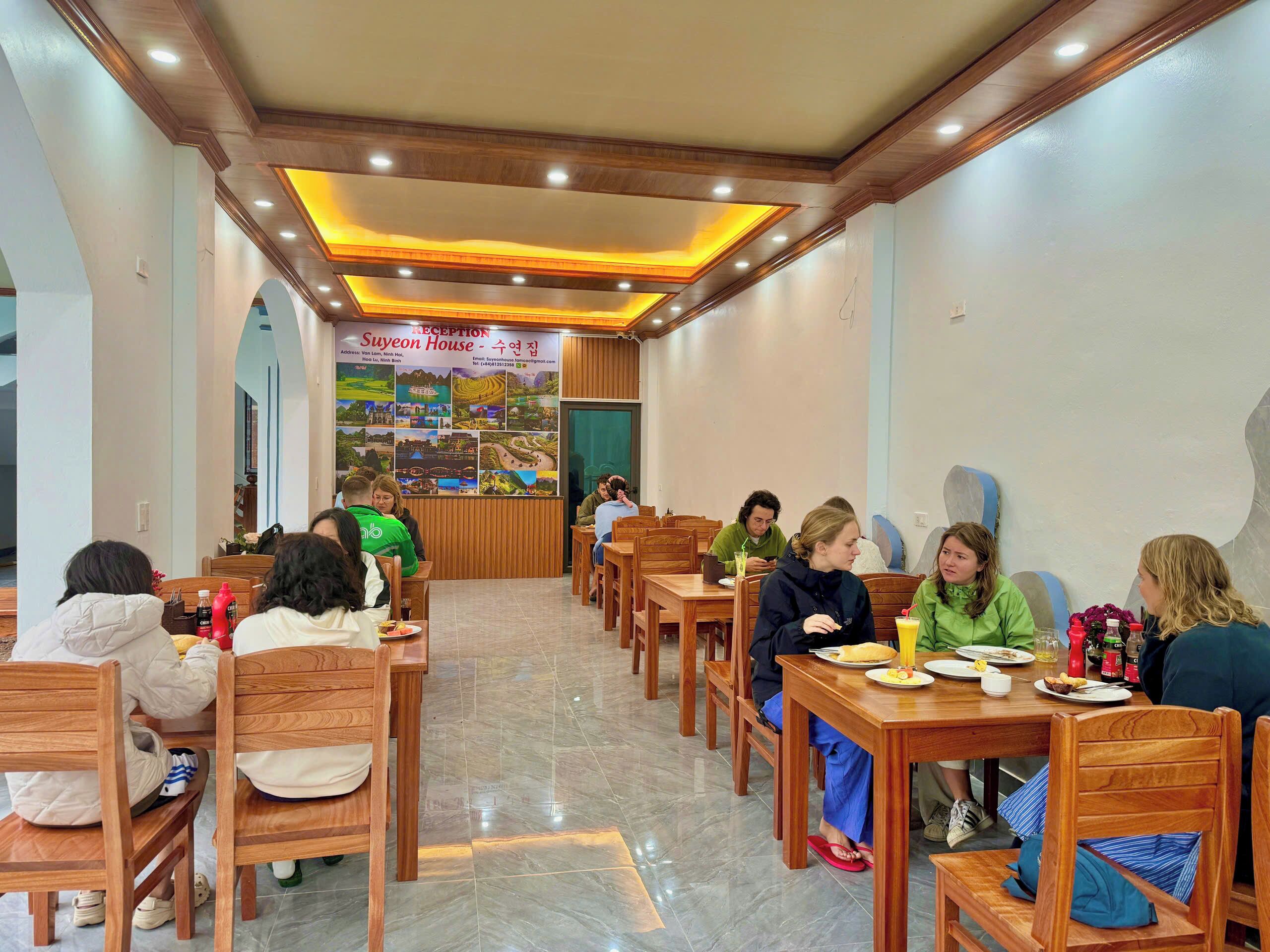 A restaurant interior with wooden furniture, a reception area, and a wall with a collage of images.
