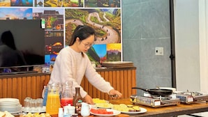 A breakfast setup with various food items and a person serving. - Tuan Ngoc Hotel (Nam Hoa Lu)