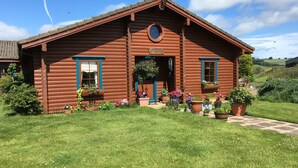 A wooden log cabin with a pitched roof, a circular window, and a door. - Balnabrechan Lodge (Arbroath)