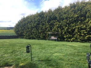 A grassy area with a swing set and a lantern post. - Balnabrechan Lodge (Arbroath)