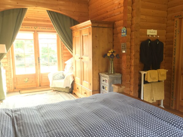 A wooden cabin room with a bed, a dresser, a vanity, and a coat rack. - Balnabrechan Lodge (Arbroath)