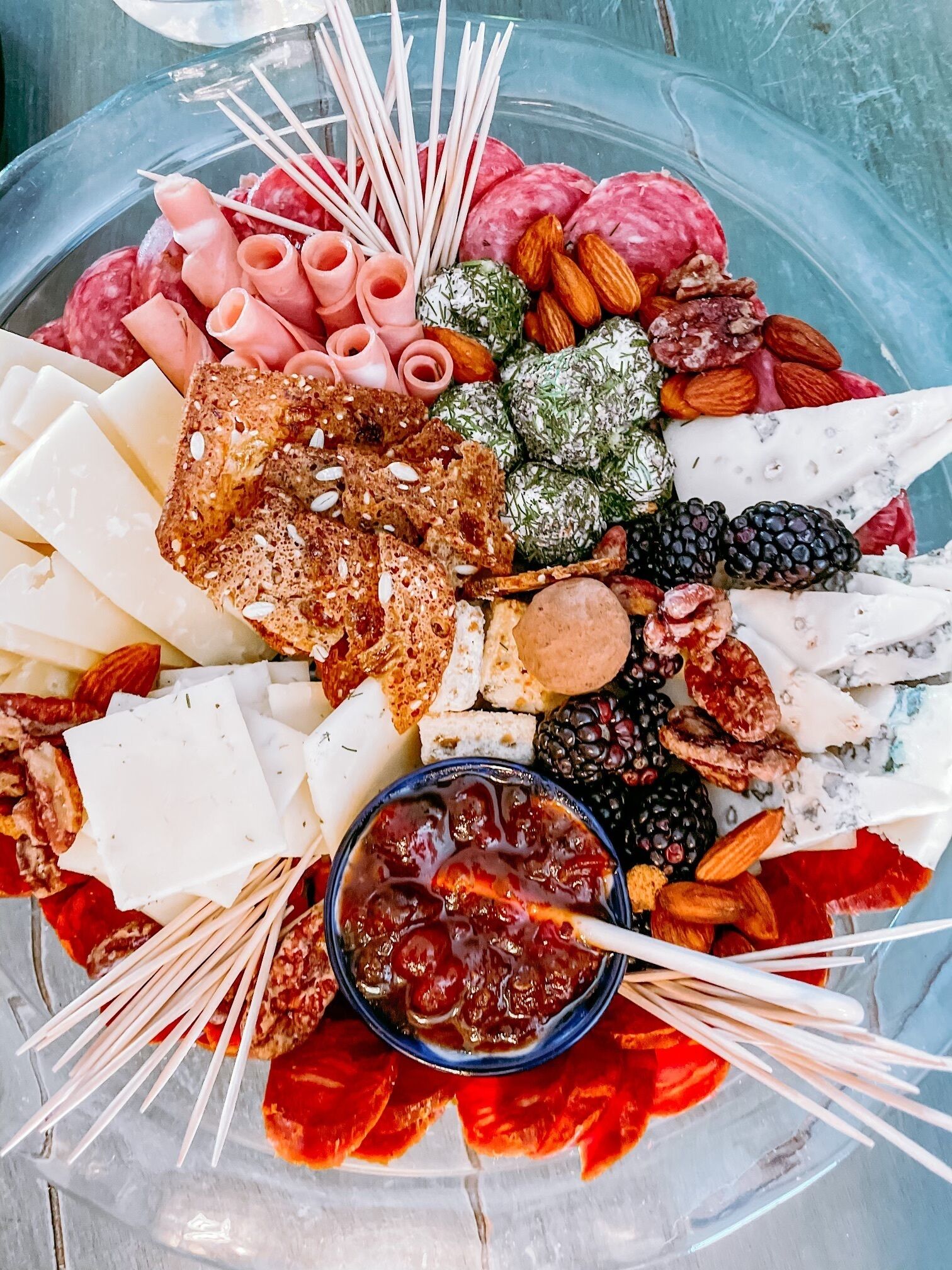 A charcuterie board with various cheeses, meats, nuts, and fruits.