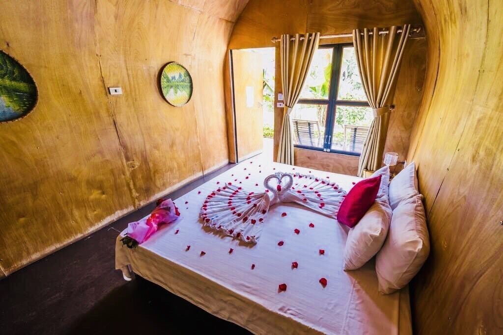 A cozy wooden room with a bed adorned with rose petals and a heart-shaped decoration.