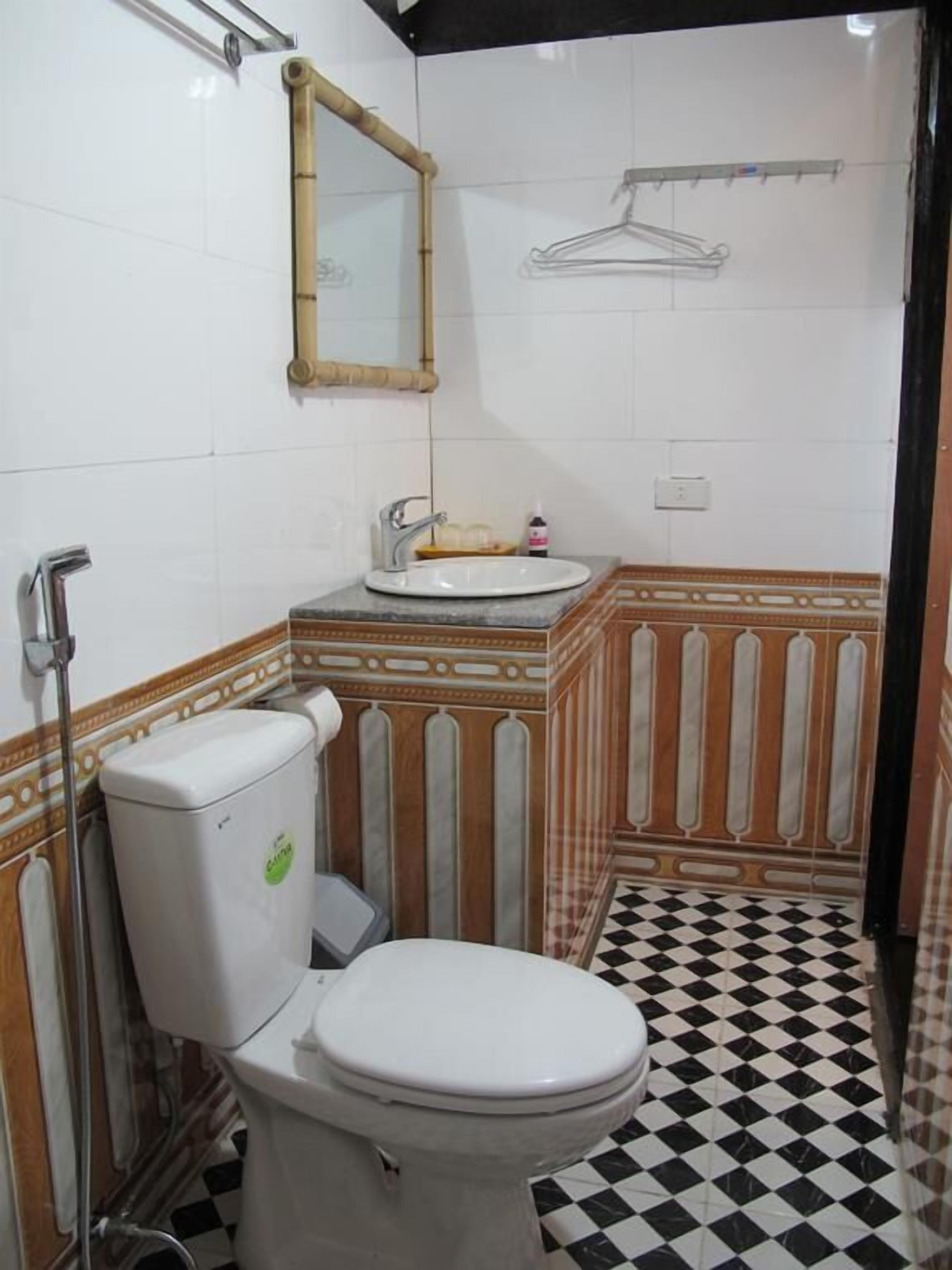 Un baño con inodoro, lavamanos y espejo.