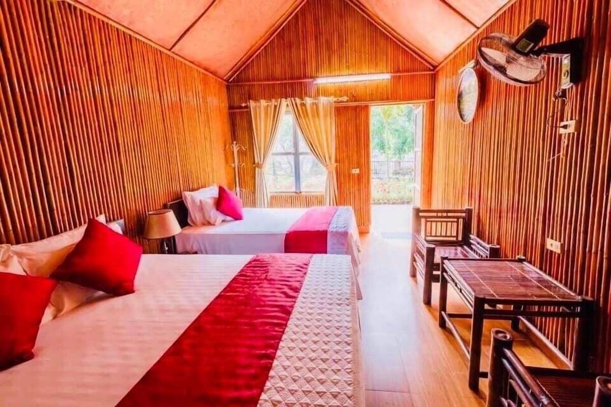 A room with two beds, a table, and a bench.