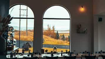 A dining area with a chandelier, large arched windows, and a view of a landscape.