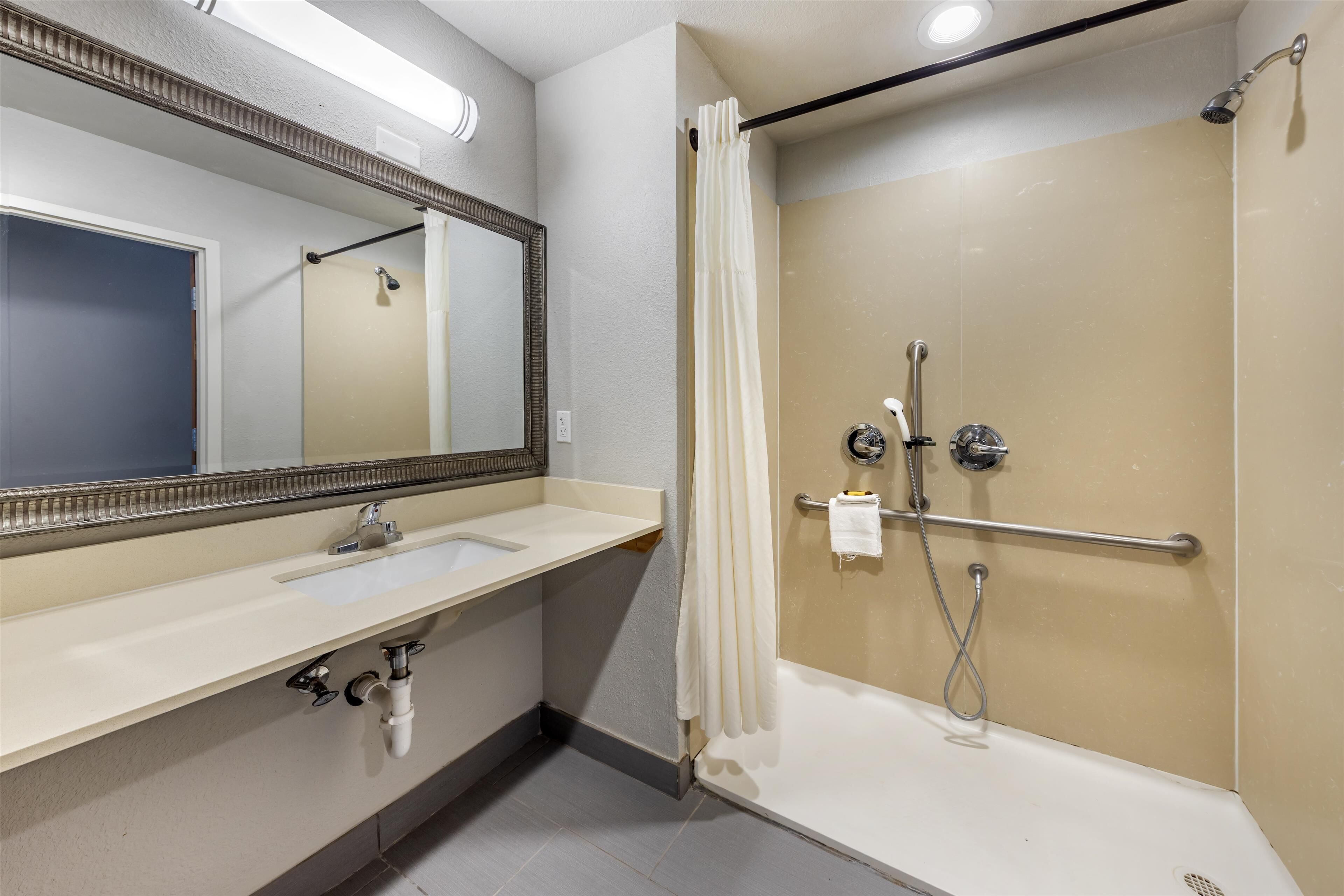 Une salle de bain équipée d’un lavabo, d’un miroir, d’une douche et d’un porte-serviettes.