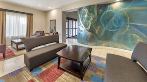 Un hall d’hôtel moderne, agrémenté d’une grande fresque murale abstraite, de sièges confortables et offrant une vue sur la pièce adjacente.