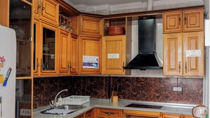 A kitchen with wooden cabinets, a stainless steel sink, and a black range hood. - Triana Backpackers (Seville)