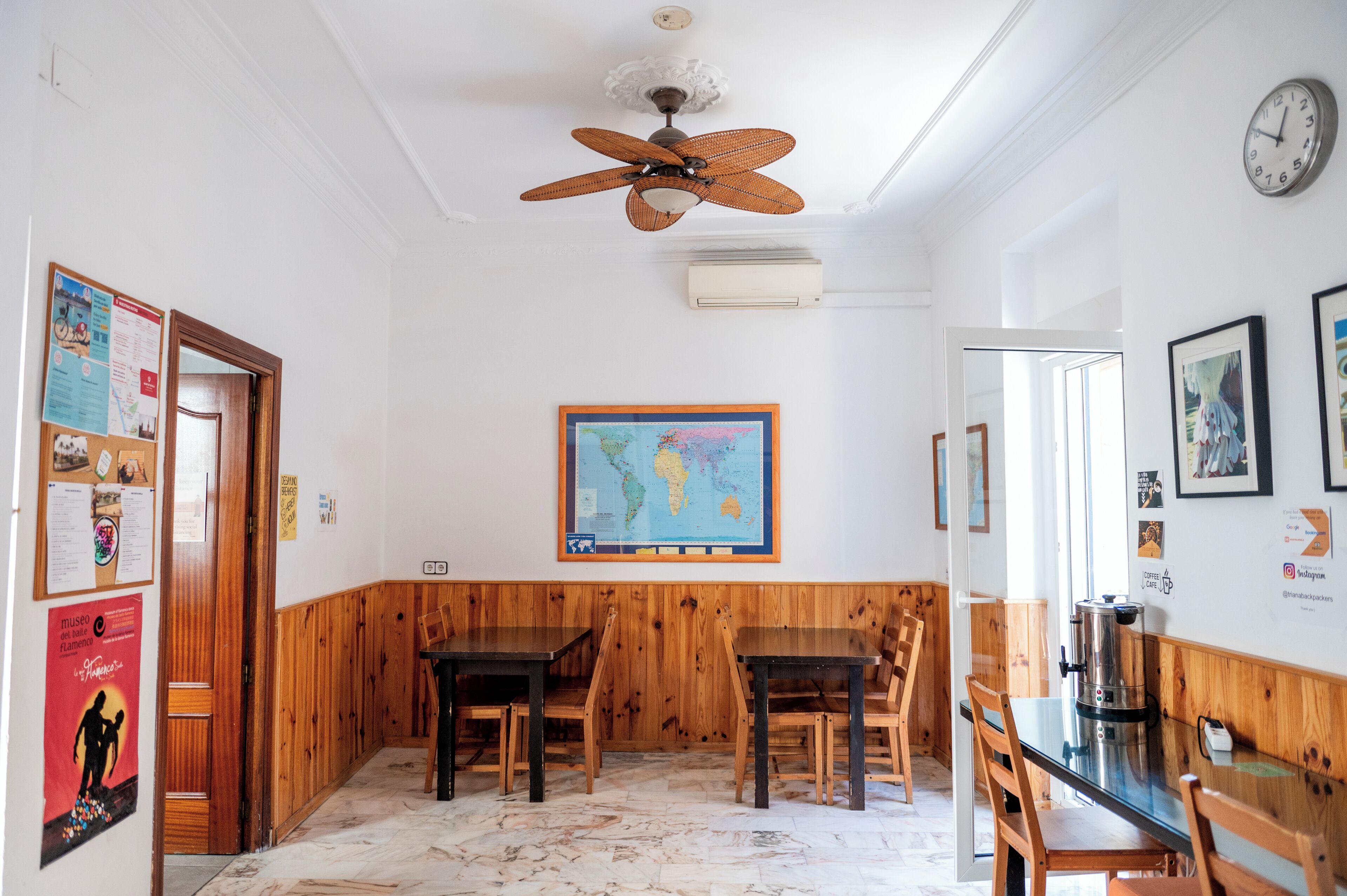 A room with wooden paneling, a ceiling fan, a map on the wall, and a coffee machine.