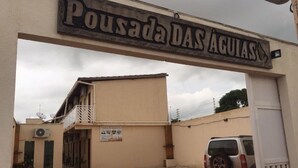 Una entrada con un letrero que dice "Pousada DAS AGUIAS" y un SUV estacionado.