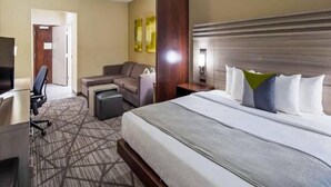 A hotel room with a bed, a desk, a chair, and a sofa. - Comfort Inn & Suites Houston I-45 North - IAH (Houston)
