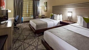 A hotel room with two beds, a desk, a chair, a TV, and a large window with curtains. - Comfort Inn & Suites Houston I-45 North - IAH (Houston)