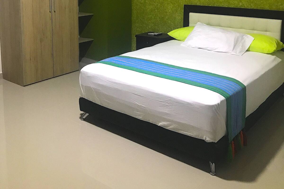 A bedroom with a bed, a wardrobe, and a green wall.