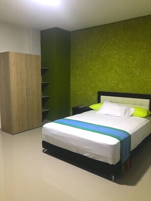 A bedroom with a bed, a wardrobe, and a green wall. - Hotel Emerawaa (Riohacha)