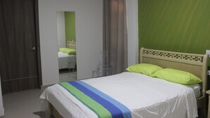 A hotel room with a bed, a mirror, a door, and an air conditioning unit. - Hotel Emerawaa (Riohacha)