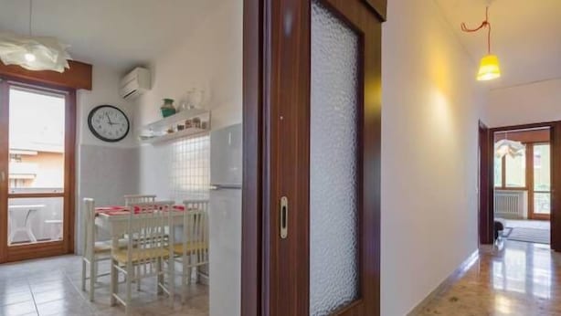 A spacious kitchen with a dining area, a clock on the wall, and a wooden door with frosted glass. - Cosy Moon Apartment (Verona)