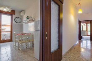 A spacious kitchen with a dining area, a clock on the wall, and a wooden door with frosted glass. - Cosy Moon Apartment (Verona)