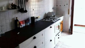 A kitchen with white cabinets, a black countertop, and a stainless steel range hood. - Cosy Moon Apartment (Verona)