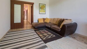 A living room with a sofa, a patterned rug, and a door leading to another room. - Cosy Moon Apartment (Verona)
