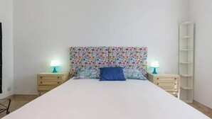 A bedroom with a white bed, floral-patterned headboard, two bedside tables with lamps, and a white wardrobe. - Cosy Moon Apartment (Verona)