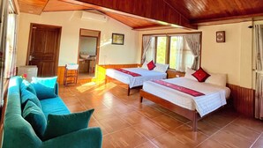 Habitación con techo de madera, dos camas, un sofá y una pequeña mesa.