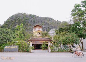 A hotel with a traditional architectural style, a signboard, and a bicycle in the foreground. - Chez Loan Hotel (Nam Hoa Lu)