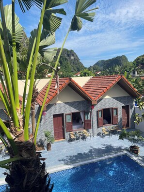 A resort with a swimming pool, a patio with outdoor seating, and a view of mountains. - Tam Coc Westlake Homestay - Hostel (Hoa Lu)