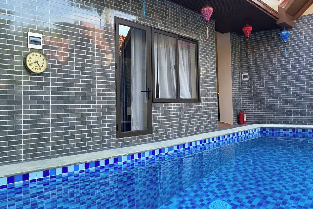 Ein Schwimmbecken mit blauen Mosaikfliesen, einer Uhr und einem Fenster mit Vorhängen.