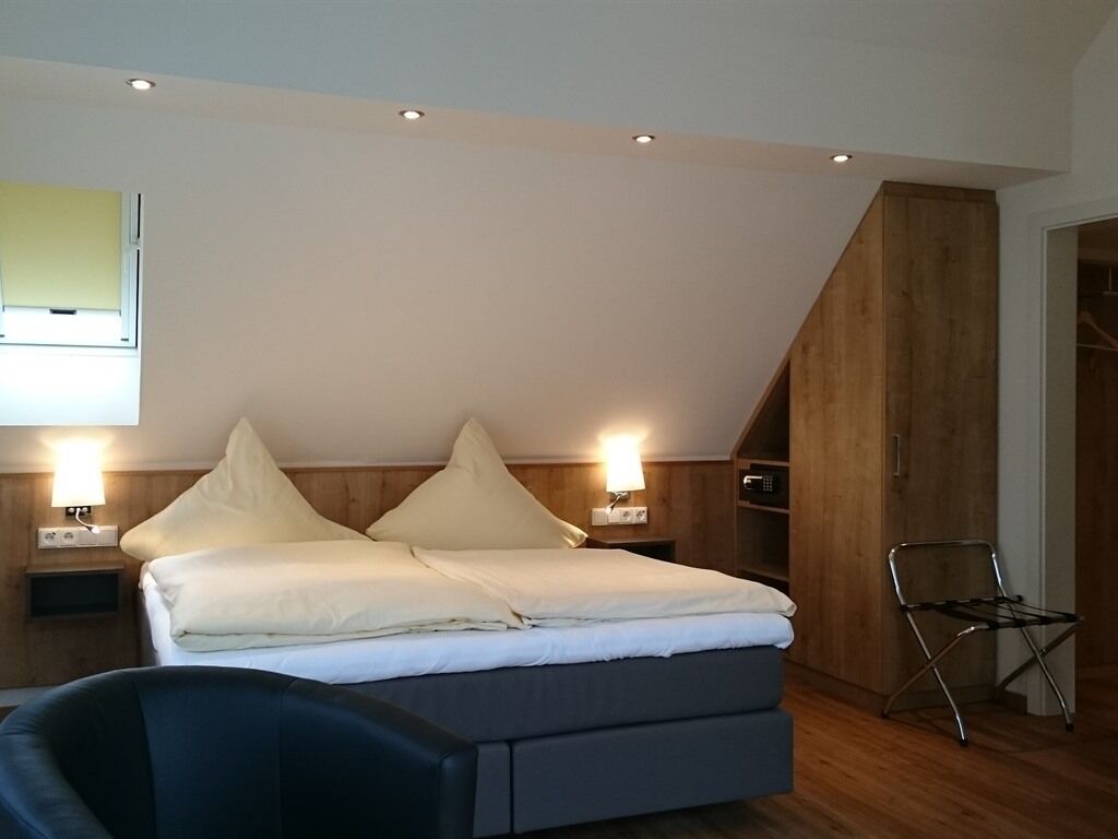 Ett modernt sovrum med en säng i loftstil, träväggar och ett takfönster.